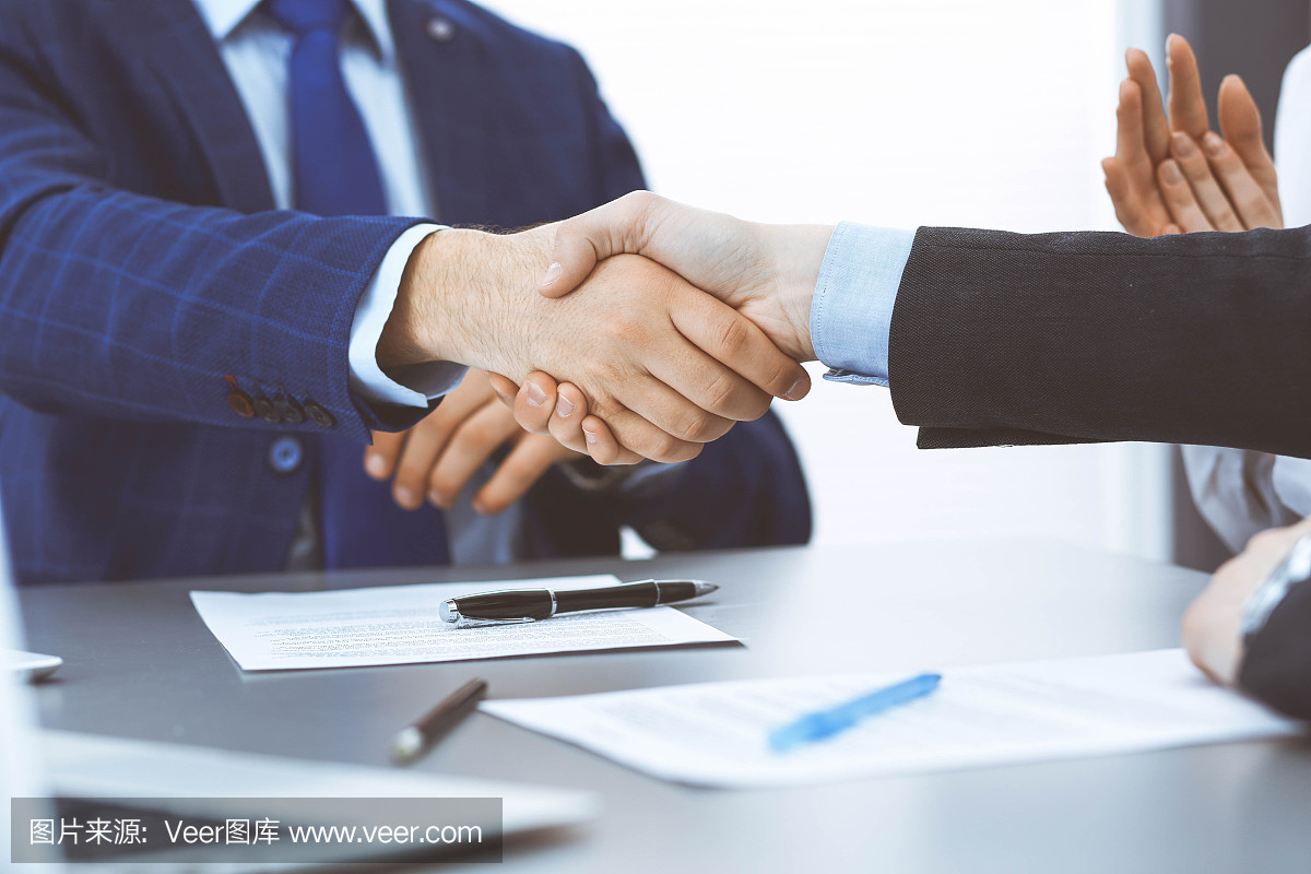 商人們握手,完成一份文件簽名。會議、合同及律師咨詢理念